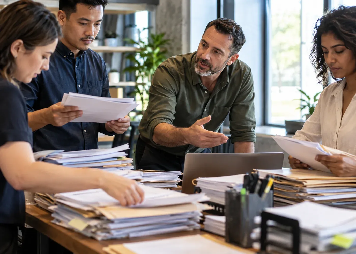 Employees work around a crowded paper handover station while their manager listens and prepares a simpler shared process with them.
